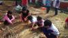 Young children use their hand shovel to make holes for the seeds.